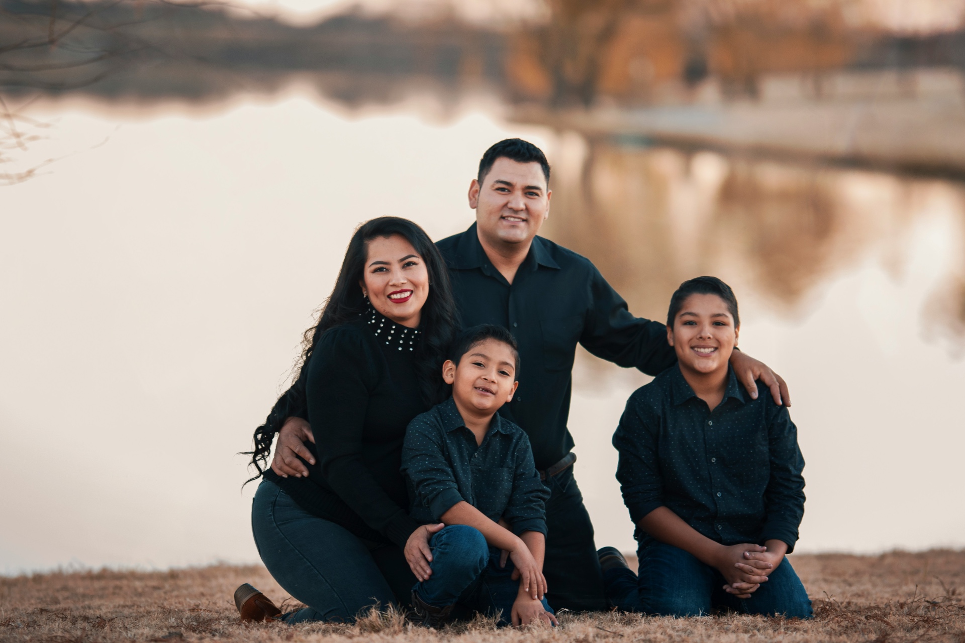 A family together outdoors by open water, warm and unposed